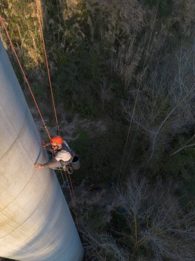 Endüstriyel tırmanışçı, özel ekipman kullanarak büyük beton yapılara iniyor.