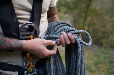 Tırmanışçı beton yapıya tırmanmak için halat ve karabinalarla tırmanmaya hazırlanıyor.