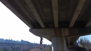 Uzman işçiler iplerden sarkıyor, beton bir otoyol üst geçidini inceliyor.