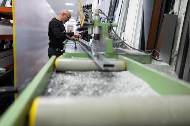 Çalışan bir atölye ortamında özel makineler kullanarak alüminyum profilleri ölçen ve kesen marangoz