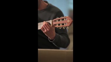 Profesyonel gitarist, klasik akustik gitarda ustalıkla akor çalarken, müzikal tutku ve teknik becerileri sergilerken ellerini yakından çerçeveliyor.