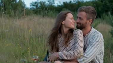 Cheerful couple enjoying picnic together, young woman and man hugging outdoors