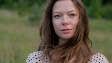 Close up portrait of young caucasian woman looking into camera outdoors