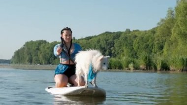 Japanese Spitz Dog Standing on Sup Board, Woman Paddleboarding with Her Pet on City Lake