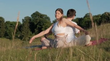 Young Adult Couple Practicing Yoga Outdoors in Nature, Woman and Man Doing Exercise Together at Sunset