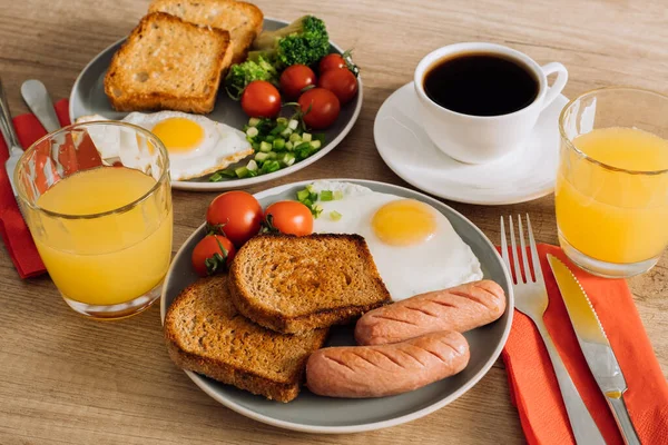 Grilled sausage and whole wheat toast with fried egg and cherry tomatoes, English breakfast with cup of coffee and orange juice