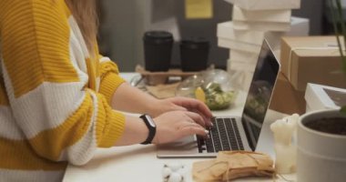 Side view of unrecognizable entrepreneur woman working on laptop in home office