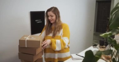 Businesswoman starting small business at home, young entrepreneur female checking boxes with goods in kitchen