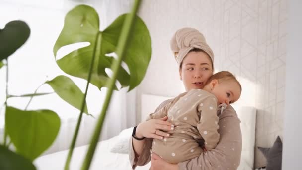 어머니는 젖꼭지를 아기를 달래며 어머니는 침실에 식물을 앞쪽에 놓는다 — 비디오