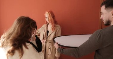 Redhead fashion model on photo shoot in studio, female photographer with male assistant at work