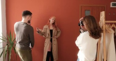 Stüdyoda fotoğraf çekimi, kadın fotoğrafçı ve erkek asistan moda modelinin fotoğraflarını çekiyor.