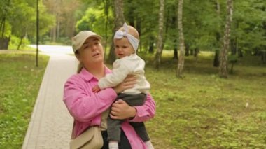 Genç bir anne, ağlayan çocuğunu parkta kucağında taşır. Yüksek kalite 4k görüntü