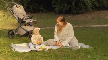 Mutlu anne güneşli bir günde çocuğuyla parkta vakit geçirir, anne ve küçük kızı dışarıda piknikte. Yüksek kalite 4k görüntü