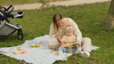 Mom with child outdoors, mother playing educational games for children with a young baby daughter at a picnic in the park. High quality 4k footage