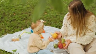 Anne, genç kızıyla parkta vakit geçiriyor. Genç anne de bebeğiyle oynuyor. Yüksek kalite 4k görüntü