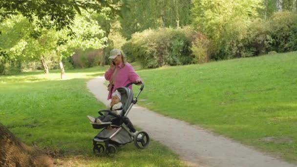 Mãe Elegante Fala Telefone Enquanto Caminha Parque Com Seu Filho — Vídeo de Stock