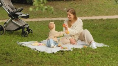 Anne, genç kızıyla parkta vakit geçirir, genç anne de bebeğiyle oynar. Yüksek kalite 4k görüntü