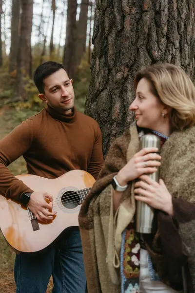 一个男人在树林里为一个女人弹奏吉他 这对成年夫妇在一起度过了一段时光 图库图片