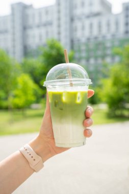 Kadınların el ele tutuşması soğuk, buzlu kibrit sütlü latte. Plastik bardakta buzlu ve samanlı. Yüksek kalite fotoğraf