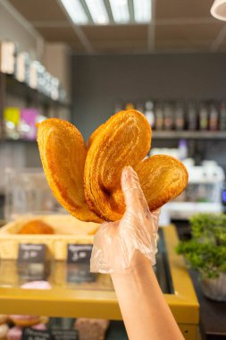 Şeffaf eldiven giymiş bir el, kahve dükkanında puf börek ve şekerli kurabiyeler tutuyor. Yüksek kalite fotoğraf