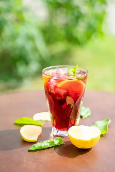 glass with fresh spring or summer iced drink mocktail with lemon and mint at table in caffe in day light. High quality photo
