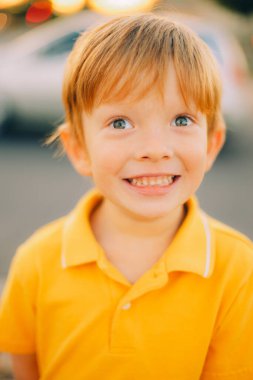 Günbatımı arka planında sarı tişörtlü, gülümseyen, mutlu, genç bir çocuğun portresi. Yüksek kalite fotoğraf