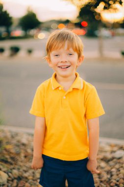 Günbatımı arka planında sarı gömlekli, gülümseyen, mutlu, genç bir çocuğun portresi. Yüksek kalite fotoğraf