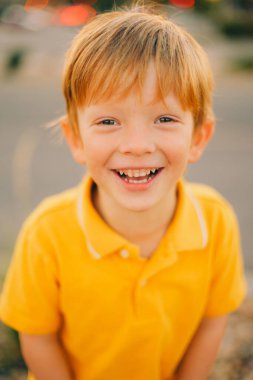 Günbatımı arka planında sarı tişörtlü, gülümseyen, mutlu, genç bir çocuğun portresi. Yüksek kalite fotoğraf