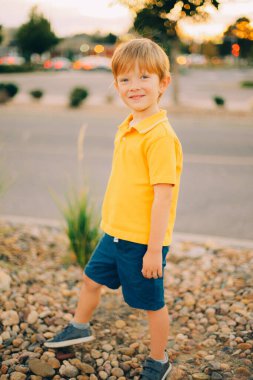 Günbatımı arka planında sarı gömlekli, gülümseyen, mutlu, genç bir çocuğun portresi. Yüksek kalite fotoğraf