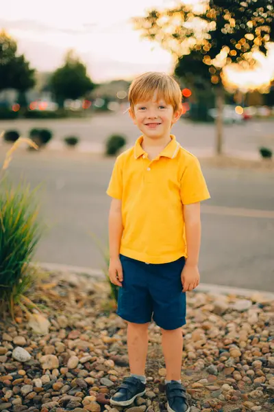 Günbatımı arka planında sarı gömlekli, gülümseyen, mutlu, genç bir çocuğun portresi. Yüksek kalite fotoğraf