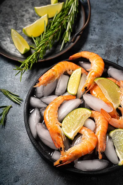 Red Argentine King shrimps ocean jumbo shrimps with lemon and rosemary on ice close up at the black background. High quality photo