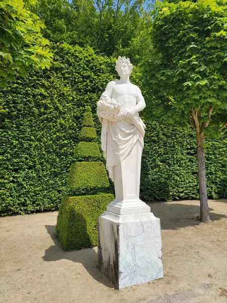 Versay 'daki bahçe tanrısı bir sepet çiçek tutuyor ve baştan çıkarmak üzere olduğu peri Pomona' ya doğru dönüyor. Versay, Fransa