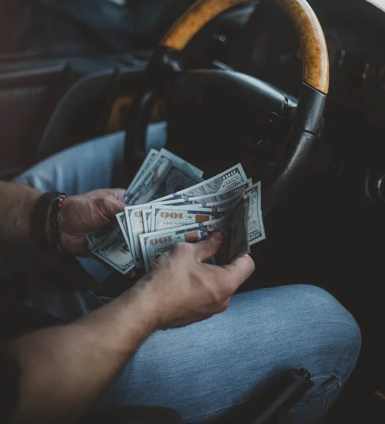 man in a car with a dollar bill counting