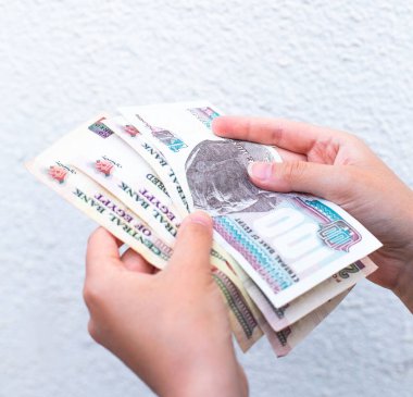 Beyaz bir duvara yaslanmış Mısır banknotlarını sayıyorum. Mısır 'da yerel para birimi, bütçe veya tasarruf konuları