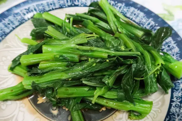 stock image close up of Chinese Hong Kong style homemade boiled Choy sum vegetables with soy sauce on a blue and white plate