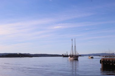 Oslo, Norveç - 27 Mart 2018: Mavi gökyüzü ve deniz yansıması ile denizde yelken açan tekne