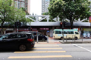 Sham Tseng, Tsuen Wan, Hong Kong - 1 Temmuz 2024: Alışveriş merkezleri ve yolları olan yerel yerleşim yerleri. Arabalar, taksiler ve otobüsler geçip gidiyor..