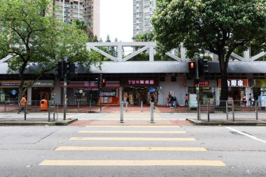 Sham Tseng, Tsuen Wan, Hong Kong- 1 July 2024: local downtown neighbourhood housing estate with shops and road. Cars, taxis and buses are crossing and passing by. clipart