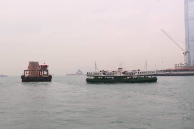 Tsim Sha Tsui, Hong Kong - 30 Ocak 2016: Yıldız feribot gemisi ve liman kenti yakınlarındaki Victoria Limanı 'nda bir kargo gemisi