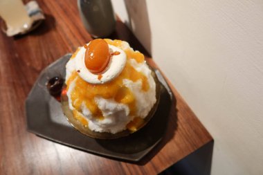 Geleneksel Japon Sobert soğuk tıraş edilmiş buzlu tatlı kakigori bingsu üzerine portakal reçeli sosu ve meyve, siyah tabakta oolong çayı sosu beyaz arka plan ve yaz aylarında ahşap masa.