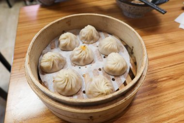 Tayvan Çin buğulama et çorbası hamur köftelerini ahşap bir masada, bambu kafesli bir konteynırda yakın plan.