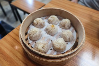 Tayvan Çin buğulama et çorbası hamur köftelerini ahşap bir masada, bambu kafesli bir konteynırda yakın plan.