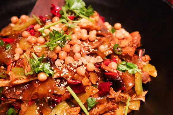 Stock image close up of Sichuan style spicy dry pot with peanut, beef tongue, beef stomach, celtuce, meat and noodles in a black bowl