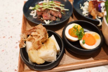 Haşlanmış yumurta, kızarmış sığır eti, ızgara balık, salata, ahşap tepside wasabi yer elması dahil olmak üzere beş farklı yemekle Japon menüsü.