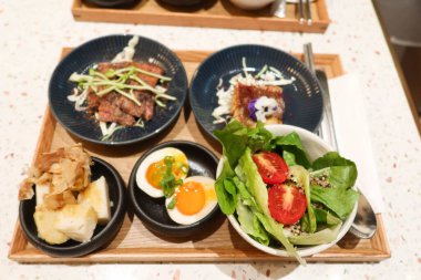 Haşlanmış yumurta, kızarmış sığır eti, ızgara balık, salata, ahşap tepside wasabi yer elması dahil olmak üzere beş farklı yemekle Japon menüsü.