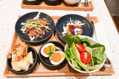 Haşlanmış yumurta, kızarmış sığır eti, ızgara balık, salata, ahşap tepside wasabi yer elması dahil olmak üzere beş farklı yemekle Japon menüsü.