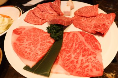 Yakiniku için beyaz tabakta yağlı çiğ Japon Matsusaka bifteği, ızgara sığır eti.