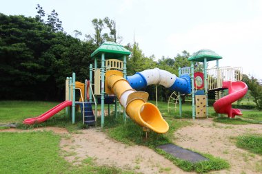 Güneşli bir günde çimen tarlasıyla parkta çekilen merdiveni renkli kaydırak.
