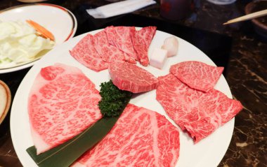 Yakiniku için beyaz tabakta yağlı çiğ Japon Matsusaka bifteği, ızgara sığır eti.