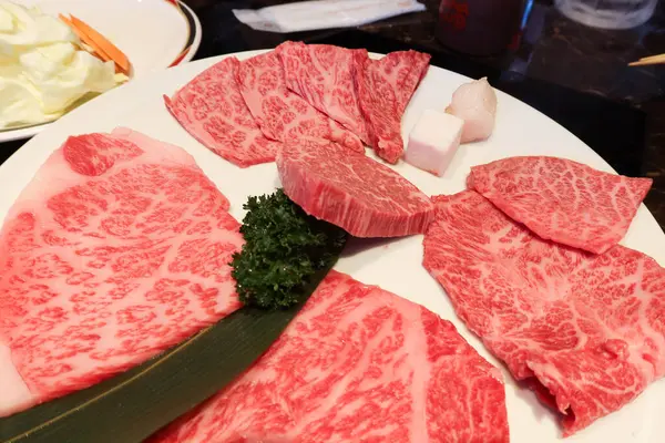 Yakiniku için beyaz tabakta yağlı çiğ Japon Matsusaka bifteği, ızgara sığır eti.